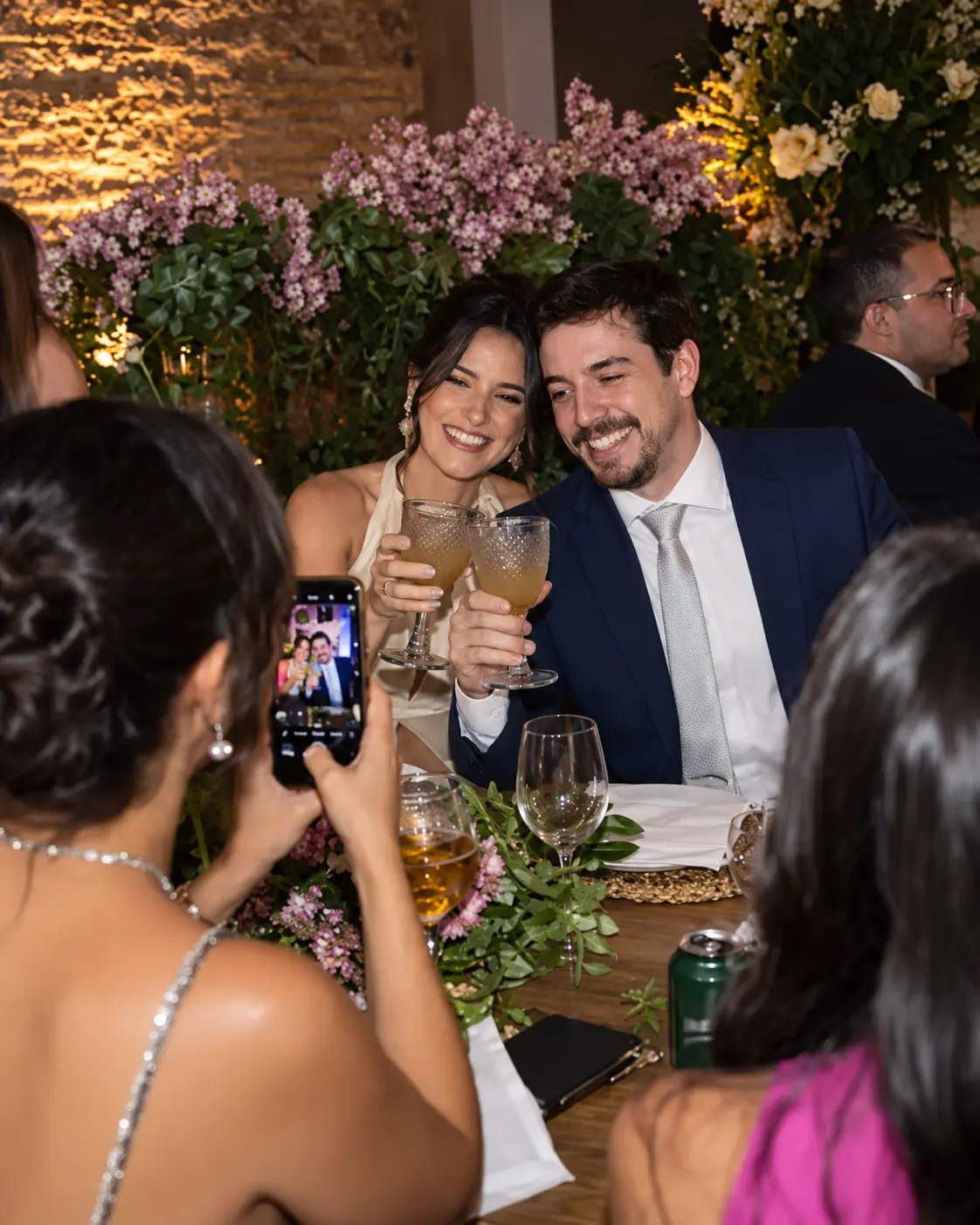 Una invitada fotografía con su celular el brindis de una pareja